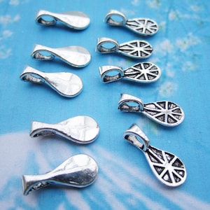 May include: Silver-toned metal pendant caps with a decorative design. The caps are shaped like teardrops and have a hole at the top for attaching to a chain or cord.
