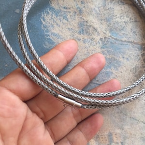 May include: A silver braided chain necklace with a magnetic clasp.