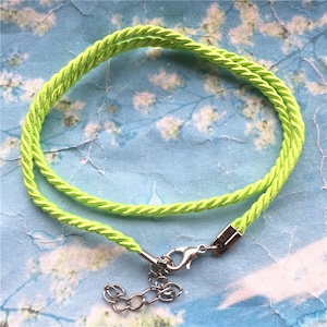 May include: A lime green braided cord necklace with a silver lobster clasp and a silver chain.