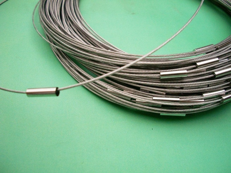 Peut inclure: Gros plan sur un c&acirc;ble argent&eacute; avec des embouts m&eacute;talliques argent&eacute;s. Le c&acirc;ble est enroul&eacute; et dispos&eacute; en cercle sur une surface verte.