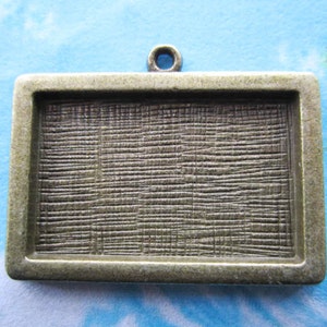 May include: A silver-toned metal frame with a textured surface. The frame has a loop at the top for hanging.