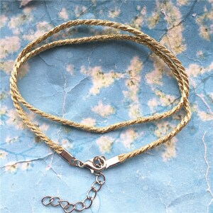 May include: A gold-colored rope chain necklace with a silver clasp and extender chain.