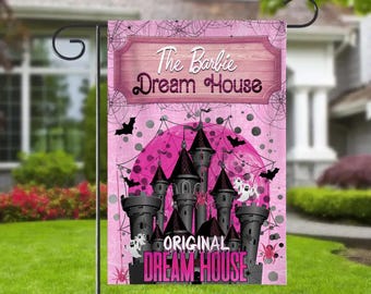 以下が含まれることがあります： 「The Barbie Dream House」と「Original Dream House」の文字が入った、城のデザインのピンクと黒のガーデンフラッグ。コウモリ、クモの巣、幽霊が描かれたピンク色の背景です。