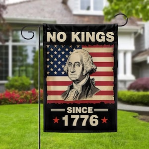 Może przedstawiać: Czarna flaga ogrodowa z napisem "NO KINGS" i "SINCE 1776". Flaga przedstawia amerykańską flagę z portretem George'a Washingtona. Dominują kolory czerwony i niebieski.