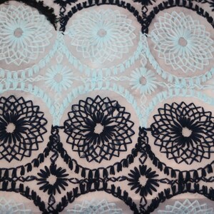 May include: Black and light blue embroidered fabric with a repeating pattern of floral designs.