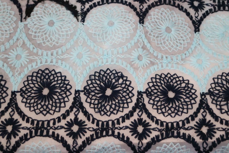 May include: Black and light blue embroidered fabric with a repeating pattern of floral designs.