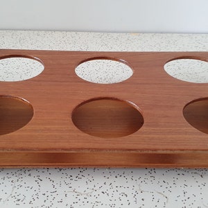 Op de afbeelding: Een houten dienblad met zes ronde uitsparingen en twee metalen handvatten. Het dienblad is bruin en heeft een natuurlijke houten afwerking.