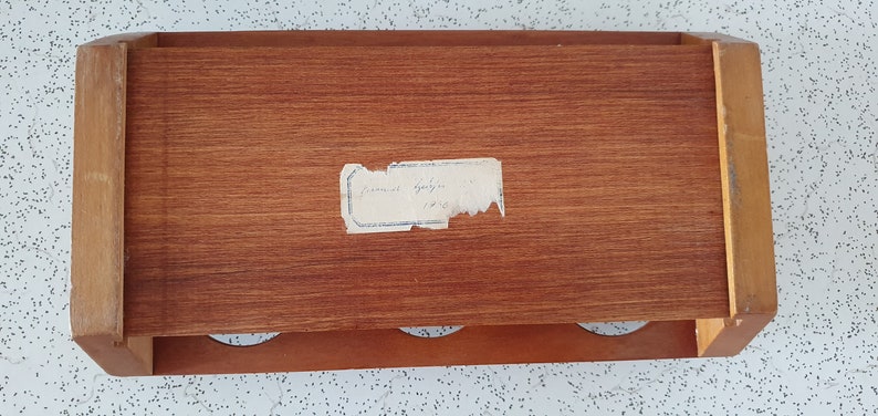 Op de afbeelding: Een houten doos met drie gaten aan de voorkant en een label met de tekst "Samuel Appleton 1745".
