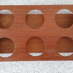 Op de afbeelding: Een houten dienblad met zes ronde uitsparingen en twee metalen handvatten. Het dienblad is gemaakt van lichtbruin hout en heeft een natuurlijke afwerking. De handvatten zijn zilverkleurig en hebben een gepolijste afwerking.