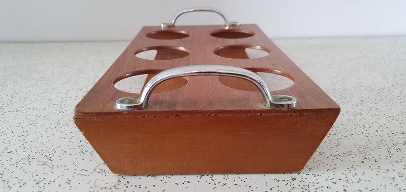 Op de afbeelding: Een houten dienblad met zes ronde uitsparingen en twee metalen handvatten. Het dienblad is bruin en de handvatten zijn zilverkleurig.