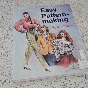 May include: A book titled "Easy Pattern-making" by Phyllis Hoffman. The cover features illustrations of three figures in fashion poses. The figures are wearing a pink top, a tan blazer, and a ruffled top. The background is a light blue.