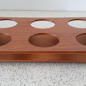 Op de afbeelding: Houten dienblad met zes ronde uitsparingen en twee metalen handvatten. Het dienblad is bruin en heeft een natuurlijke houten afwerking.
