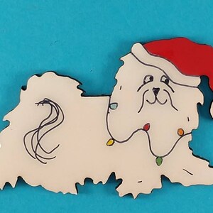 May include: A white dog-shaped Christmas ornament wearing a red Santa hat and a string of colorful lights. The dog has black outlines and a whimsical design, perfect for holiday decor.