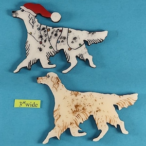 May include: Two dog-shaped ornaments. One is white with black spots, a red Santa hat, and a string of colorful lights. The other is cream-colored with brown markings. The yellow tag reads "3" wide."