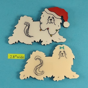 May include: Two decorative dog-shaped ornaments. One is white with a red Santa hat and string lights. The other is cream-colored with a blue bow. Both are 2.8 inches wide.