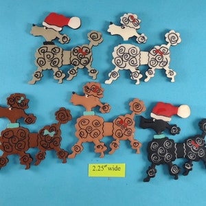 May include: A collection of wooden poodle ornaments in various colors, including brown, black, and white, with curly fur details. Some poodles wear Santa hats or have decorative bows. Each ornament is approximately 2.25 inches wide.