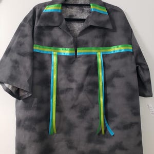 May include: A gray, short-sleeved shirt with a tie-dye pattern. The shirt features a collar and is decorated with horizontal stripes and vertical ribbons in shades of blue and green.