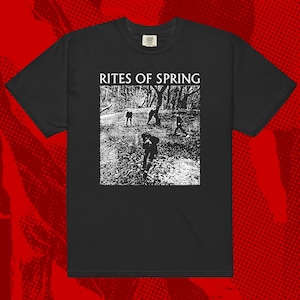Puede incluir: Camiseta negra con un gráfico blanco. El gráfico incluye el texto "RITES OF SPRING" sobre una imagen en blanco y negro de figuras en un bosque. La camiseta tiene cuello redondo y mangas cortas.