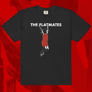 May include: Black t-shirt with white text that reads "THE FLATMATES" and a white silhouette of a woman in a red dress jumping.
