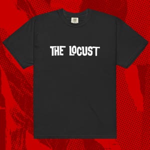 Puede incluir: Camiseta negra con el texto blanco "THE LOCUST" en el pecho. La camiseta tiene mangas cortas y cuello redondo. El fondo es rojo con un patrón de semitono.