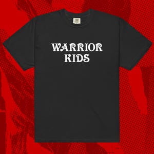 Può includere: T-shirt nero con la scritta bianca "WARRIOR KIDS" in un carattere audace e stilizzato. La maglietta ha maniche corte e girocollo. Lo sfondo è un motivo a mezzitoni rosso.