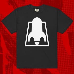 May include: Black t-shirt with a white graphic of a rocket ship inside a square.
