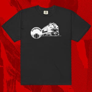 May include: Black t-shirt featuring a white graphic of a train and the word "knapsack" in a circular design. The train illustration includes details like the engine's front and side. The shirt is a crew neck style.