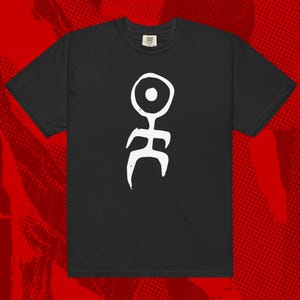 May include: Black t-shirt with a white abstract design. The graphic includes a circle, a vertical line, and curved shapes. The t-shirt is made of a soft material.
