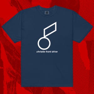 Puede incluir: Camiseta azul marino con un diseño geométrico blanco y el texto "christie front drive". El diseño incluye un círculo y un rombo. La camiseta está hecha de un material suave.