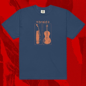 Pode incluir: Camiseta azul marinho com um design serigrafado. O design apresenta a palavra "*braid*" acima de duas ilustrações laranja de um violoncelo e um violino. A camiseta tem gola redonda e mangas curtas.