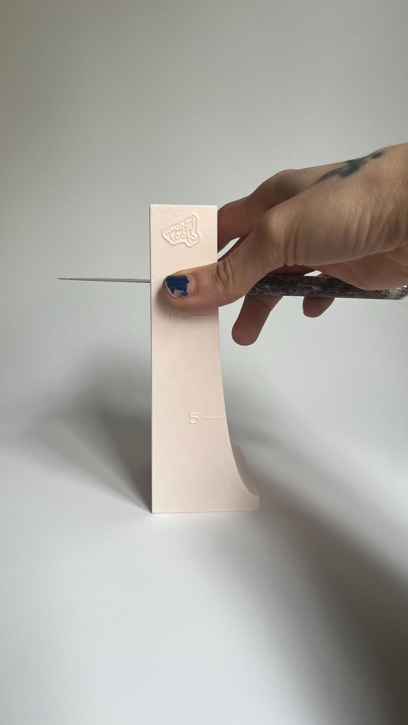 May include: A pink plastic tool with the words "Sugar Tools" embossed on it. The tool has a curved edge and markings for 5 and 10 inches.