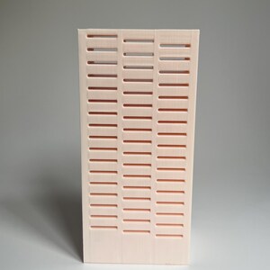 May include: A pale pink, rectangular, decorative wall panel with a grid pattern of horizontal slots.