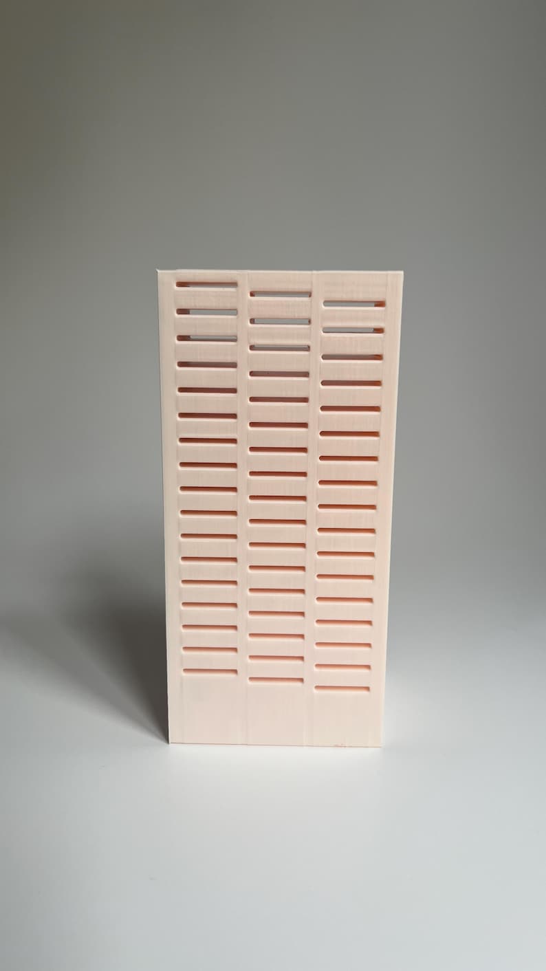 May include: A pale pink, rectangular, decorative wall panel with a grid pattern of horizontal slots.