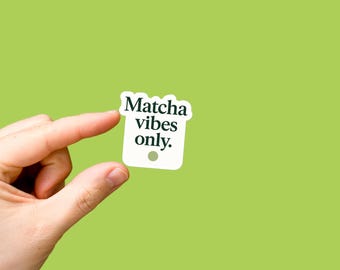 Può includere: Un adesivo bianco con la scritta "Matcha vibes only" in un carattere verde scuro. L'adesivo è tenuto tra le dita su uno sfondo verde chiaro. L'adesivo ha un piccolo punto verde chiaro in basso.