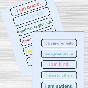 Op de afbeelding: Twee vellen papier met positieve affirmaties erop gedrukt. De affirmaties zijn in kleurrijke tekst en worden omringd door zwarte randen. De affirmaties omvatten "Ik ben dapper", "Ik ben geliefd", "Ik zal nooit opgeven", "Ik kan om hulp vragen", "Ik ben een goede luisteraar", "Ik ben aardig", "Ik luister naar anderen", en "Ik ben geduldig".