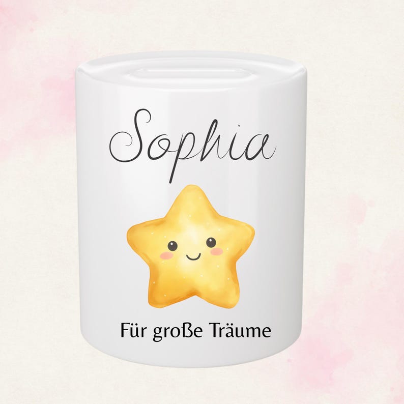 May include: White ceramic bank with the name "Sophia" in black script above a smiling yellow star. Below the star, the text "F&uuml;r gro&szlig;e Tr&auml;ume" is printed in black. The bank has a cylindrical shape.