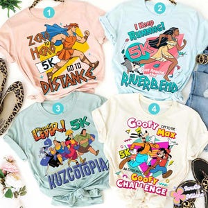 May include: Four graphic t-shirts with cartoon characters and text related to running. The shirts are light pink, light blue, and off-white. The designs include Hercules, Pocahontas, Kuzco, and Goofy. The text includes "Zero to Hero 5K", "I Keep Running! 5K", "Wrong Lever! 5K", and "Goofy Off to the Max 5K".