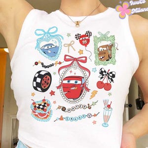 Puede incluir: Top blanco sin mangas con un estampado gr&aacute;fico de Cars. El estampado presenta a Rayo McQueen, Mate y otros personajes de la pel&iacute;cula. El texto "Mater" y "Sally" tambi&eacute;n est&aacute; incluido en el estampado.
