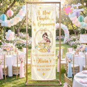 May include: A cream-colored banner with gold text and a Belle illustration, framed by a gold metal stand. The banner reads "A New Chapter Is Beginning" and "Olivia's Royal Baby Shower July 20, 2026". The background features party decorations.