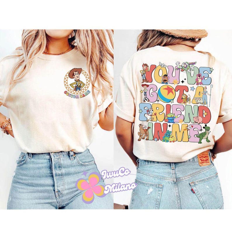 May include: Two women wearing white t-shirts with Toy Story characters and the text "You've got a friend in me". The women are wearing blue jeans.