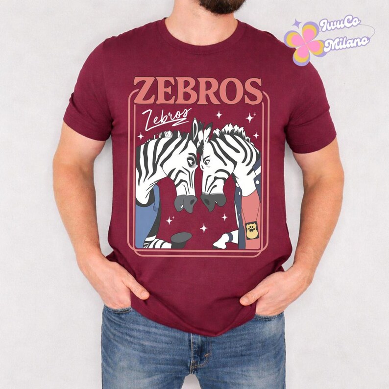 May include: Maroon t-shirt featuring a graphic of two zebras facing each other, with the text "ZEBROS" above and "Zebros" below. The zebras are in a rectangular frame with stars. The shirt is short-sleeved.