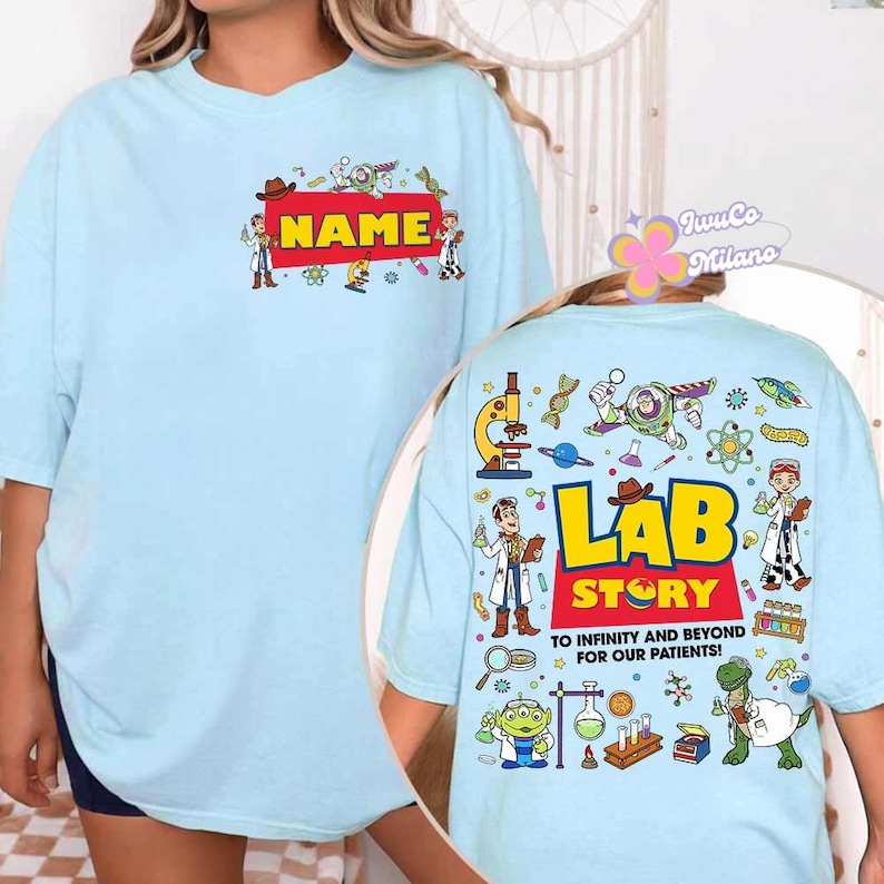 May include: Light blue t-shirt with a red rectangle that says "NAME" in yellow. The back of the shirt has the words "LAB STORY" and "TO INFINITY AND BEYOND FOR OUR PATIENTS!" with cartoon characters and science-themed graphics.