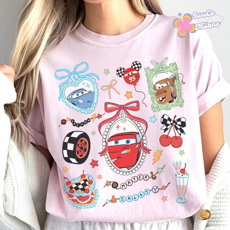 Puede incluir: Camiseta rosa con un estampado gr&aacute;fico de coches de dibujos animados, corazones, cerezas y un batido. El texto "Mater" y "Sally" est&aacute; impreso en la camiseta.