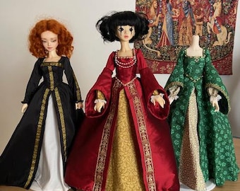 May include: Three dolls wearing different renaissance era gowns. The doll on the left is wearing a black gown with gold trim, the doll in the middle is wearing a red gown with gold trim and a gold patterned skirt, and the doll on the right is wearing a green gown with a floral pattern.