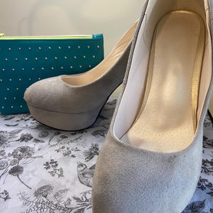 May include: A pair of gray suede platform heels. The heels are about 4 inches tall and have a closed toe.