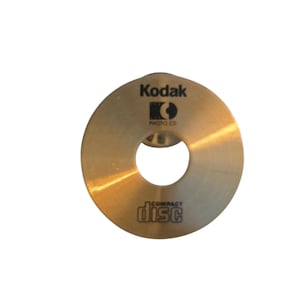 Könnte beinhalten: Eine goldfarbene Kodak Photo CD mit einem zentralen Loch, mit dem "Kodak"-Logo und dem Text "PHOTO CD" über dem Loch. Das "compact disc"-Logo ist darunter aufgedruckt.