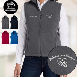 May include: A gray fleece vest with a full zipper, featuring the embroidered text "Pediatric Case Manager" and "Parker, RN." Additional vests in gray, navy, red, and blue are displayed. The vest has a high collar and two side pockets.