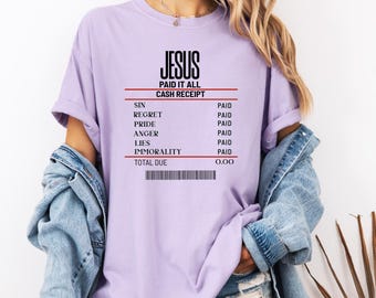 Könnte beinhalten: Ein helllila T-Shirt mit dem Text "JESUS PAID IT ALL CASH RECEIPT". Die Quittung listet "SIN, REGRET, PRIDE, ANGER, LIES, IMMORALITY" als bezahlt auf. Der Gesamtbetrag ist 0,00. Das T-Shirt hat einen lässigen Stil.