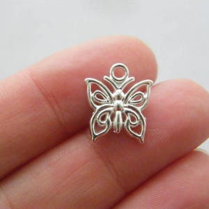 May include: Silver-toned metal butterfly charm with an intricate design. The charm has a loop at the top for attaching to jewellery or other crafts.