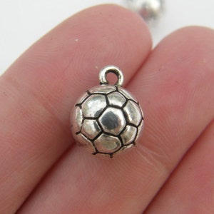 May include: Silver charm in the shape of a football. The charm has a detailed design with a textured surface.